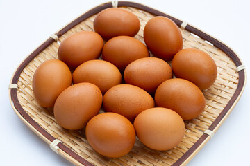 Chicken eggs in bamboo basket on white.
