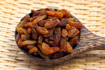 Dried grape raisins in wooden spoon
