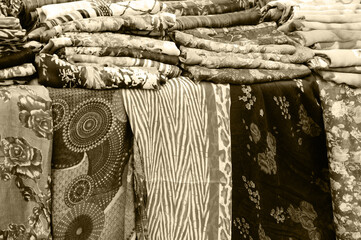 Variety of colorful shawls at street bazaar. Textile background. Sepia photo.