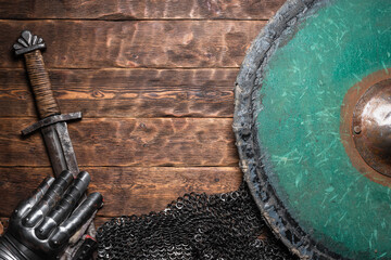 Knight armor, shield and ancient sword on the old wooden flat lay table background with copy space....
