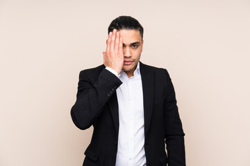 Asian business man isolated on beige background covering a eye by hand