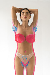 Woman sending air kiss to camera while posing over creative glass with unshaven armpits