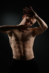 Fototapeta na wymiar A slender athletic man on a dark background.
