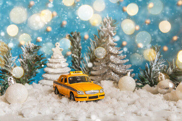 Christmas banner Background. Yellow toy car Taxi Cab model and winter decorations ornaments on blue...