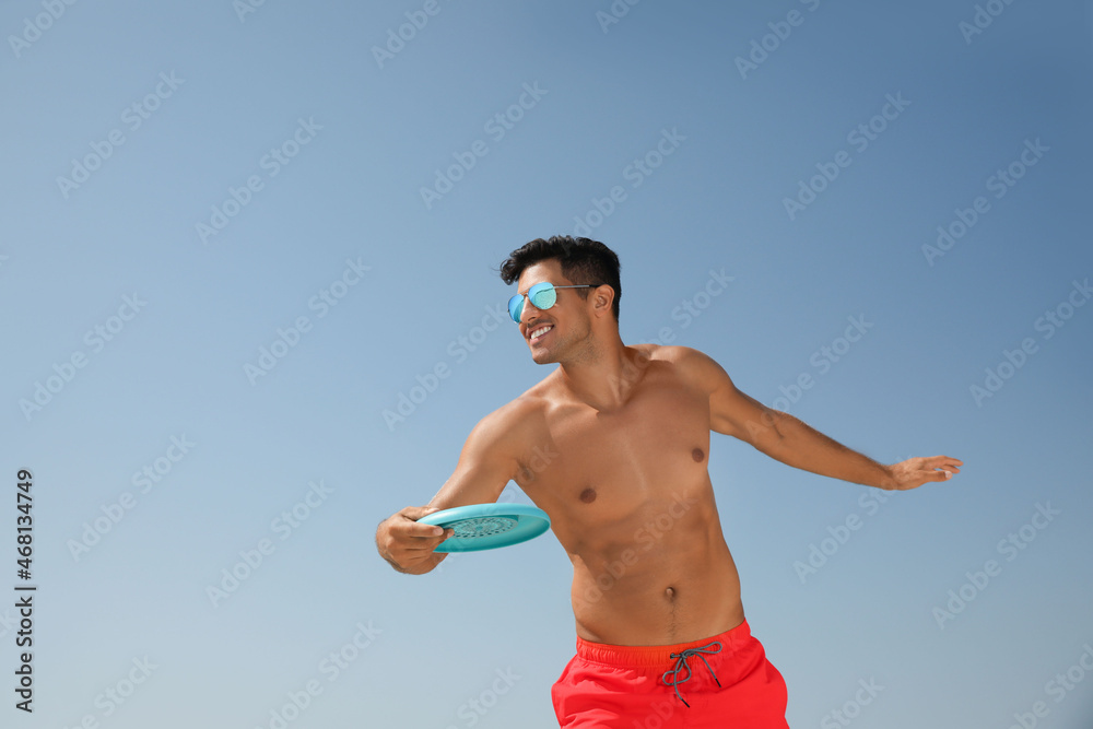 Sticker Happy man throwing flying disk against blue sky on sunny day