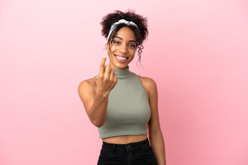 Young latin woman isolated on pink background doing coming gesture