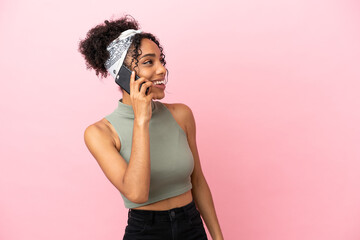 Young latin woman isolated on pink background keeping a conversation with the mobile phone
