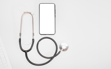 Fototapeta na wymiar Stethoscope or phonendoscope on a white background next to the phone with a cut-out place for text on a natural wood background: online medical consultation, doctoral conference