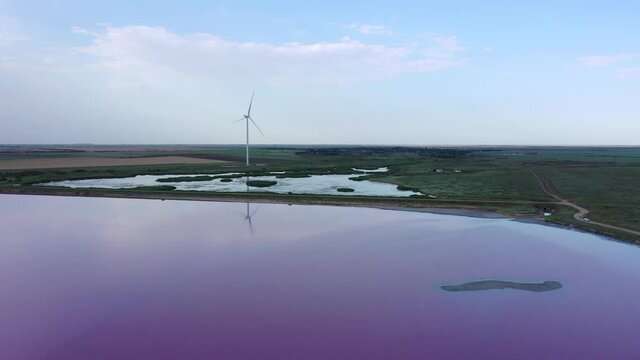 Wind turbine on the shore of a pink lake. Lake Lemuria (Pink Lake) is a lake in the Kherson region of Ukraine. Aerial view