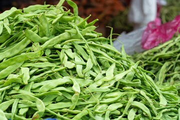 Huge pile of green string beans on the market . Concept or realism, vegan healthy food, organic bio-products market.