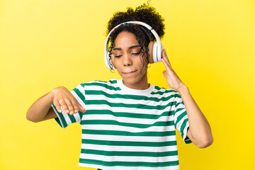 Young african american woman isolated on yellow background listening music and dancing