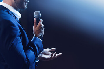 Motivational speaker with microphone performing on stage, closeup. Space for text - Powered by Adobe