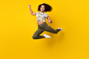 Fototapeta na wymiar Full size photo of young excited african girl rejoice winner success jump isolated over yellow color background