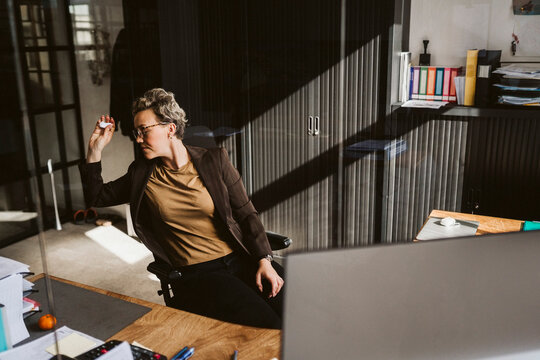 Female entrepreneur throwing paper while sitting at desk