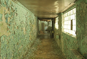 Old, scary hallway with green cracked paint, radiators and windows. Forgotten, abandoned ghost town Skrunda, Latvia. Former Soviet army radar station.