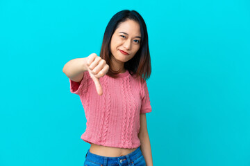 Young Vietnamese woman isolated on blue background showing thumb down with negative expression