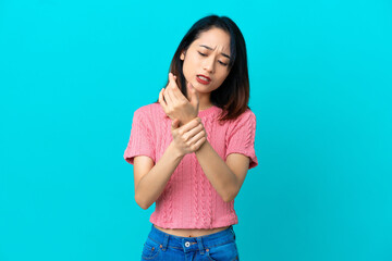 Young Vietnamese woman isolated on blue background suffering from pain in hands
