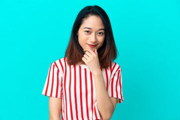 Young Vietnamese woman isolated on blue background thinking an idea while looking up