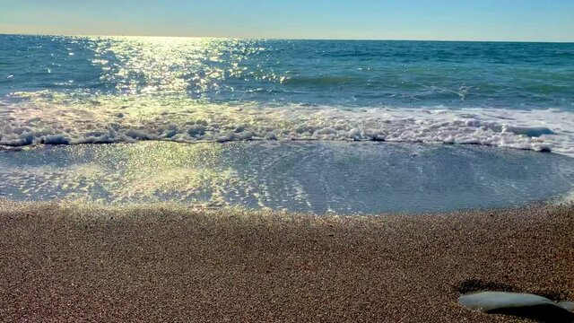 Blue sea and blue clouds, a white wave splashes on the shore, washing the beach with fine stone sand. Pacification. High quality 4k footage