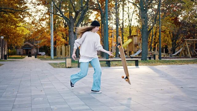 Female skateboarder doing cross-step on her longboard while walking in the park. Young woman demonstrates jumps and tricks on a skateboard