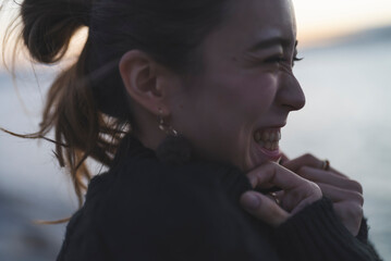 夕暮れの海を散策するクールな女性