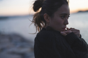 夕暮れの海を散策するクールな女性