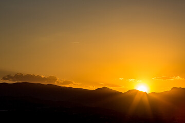 Sunlight diffraction at sunset over a mountain range in Andalusia, Spain