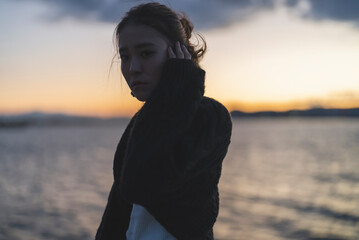 夕暮れの海を散策するクールな女性