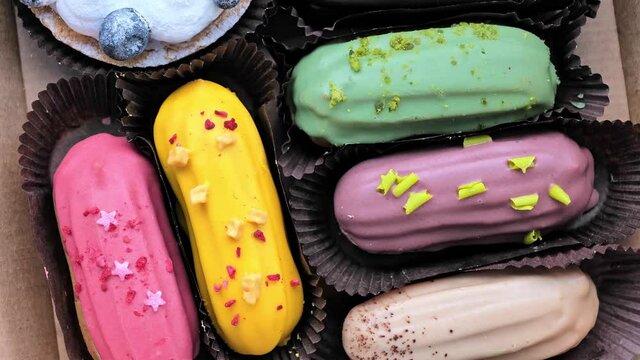 group of delicious colorful eclairs and pastries with glaze, cream, berries. Confectionery desserts for candy bar