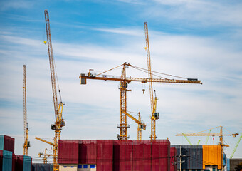 Panorama with many tower cranes in clear blue sky with clouds