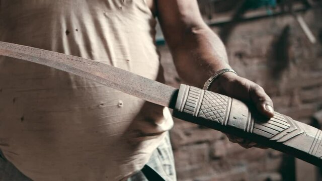Man presenting old rusty kukri knife in wooden sheath