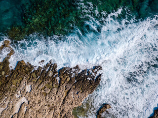 Top view of sea waves and rocky coastline