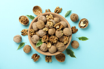Walnuts in wooden bowl on blue background