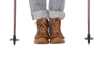 Woman wearing stylish hiking boots with trekking poles on white background, closeup