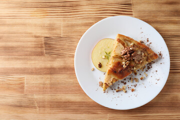 Piece of apple pie on plate on wooden background