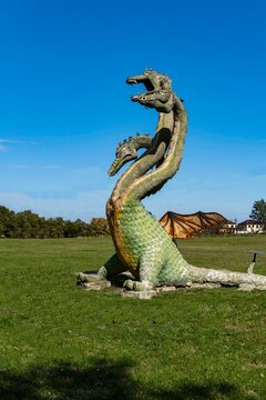 Fabulous animal Dragon with three heads, wings and tail against blue sky. Close-up. Jurassic Park in suburbs of Krasnodar. All heads look in different directions. Krasnodar, Russia - October 2, 2021
