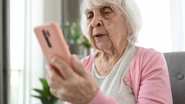 Senior woman using smartphone for video call and talking. Elderly female person with cell phone smiling at home