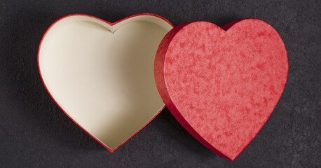 Gift box in the form of a red heart on a satin beige fabric. Concept for Valentine's Day. A gift for a loved one.