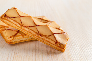 Close-up of two Italian crispy bakery Sfogliatine glassate biscuits over white wooden table. Tasty puff pastries with an apricot glase for sweet breakfast. Phyllo pastry.