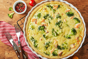 Homemade quiche with red fish, salmon, broccoli and cheese on wooden background