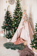 Christmas trees with children’s teepee decorated with garlands. © Alena Vilgelm