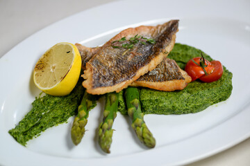 fish fillet with asparagus in a beautiful serving with lemon and cherry tomato

