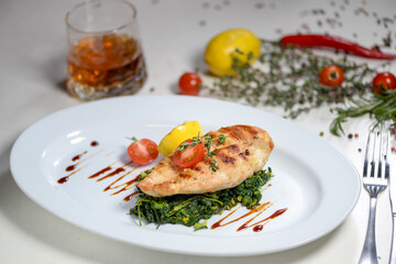grilled salmon steakgrilled chicken fillet on a spinach pillow in a white plate
