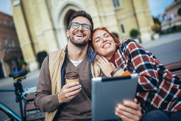 Trendy young couple in town using tablet and credit card.