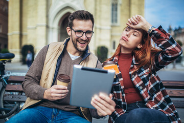 Trendy young couple in town using tablet and credit card.