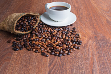 cup of coffee and coffee beans in a sack on Brown background