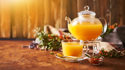Glass teapot and sea buckthorn tea cup on wooden background