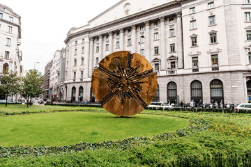Bronze sculpture of Disco Grande on the green lawn in front of the building. Italy, Milan