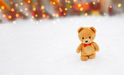 Teddy bear in Christmas walking in the snow, blurry background. New year banner. Copy space