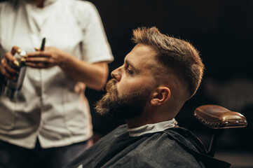 Profile of a young bearded man sitting at a barbershop